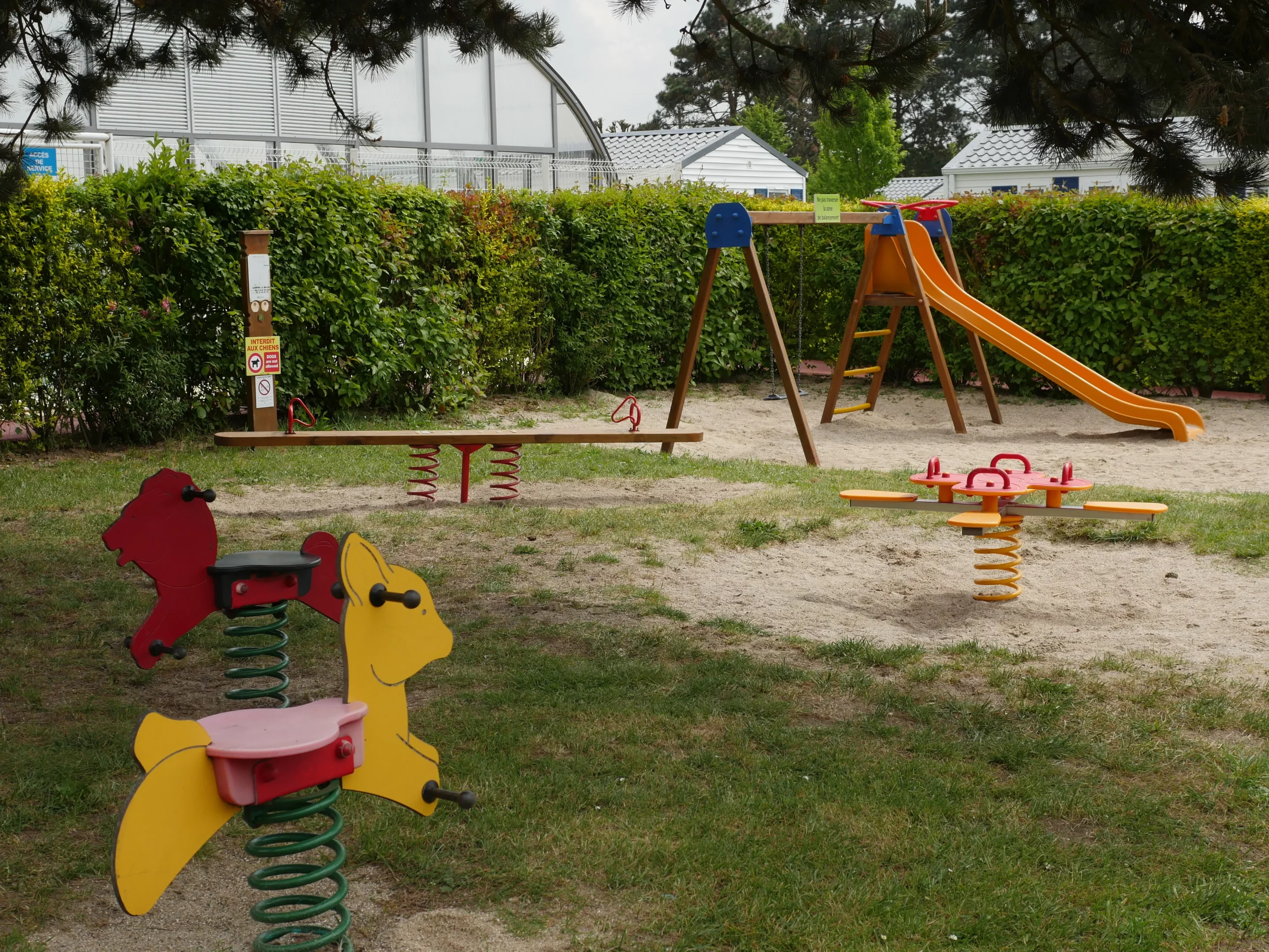 Aire de jeux colorée avec balançoires et toboggan.