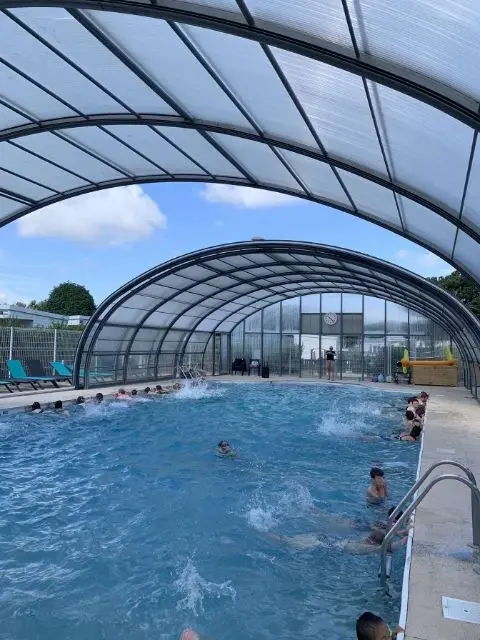 Piscine couverte avec des nageurs et une structure en arc.