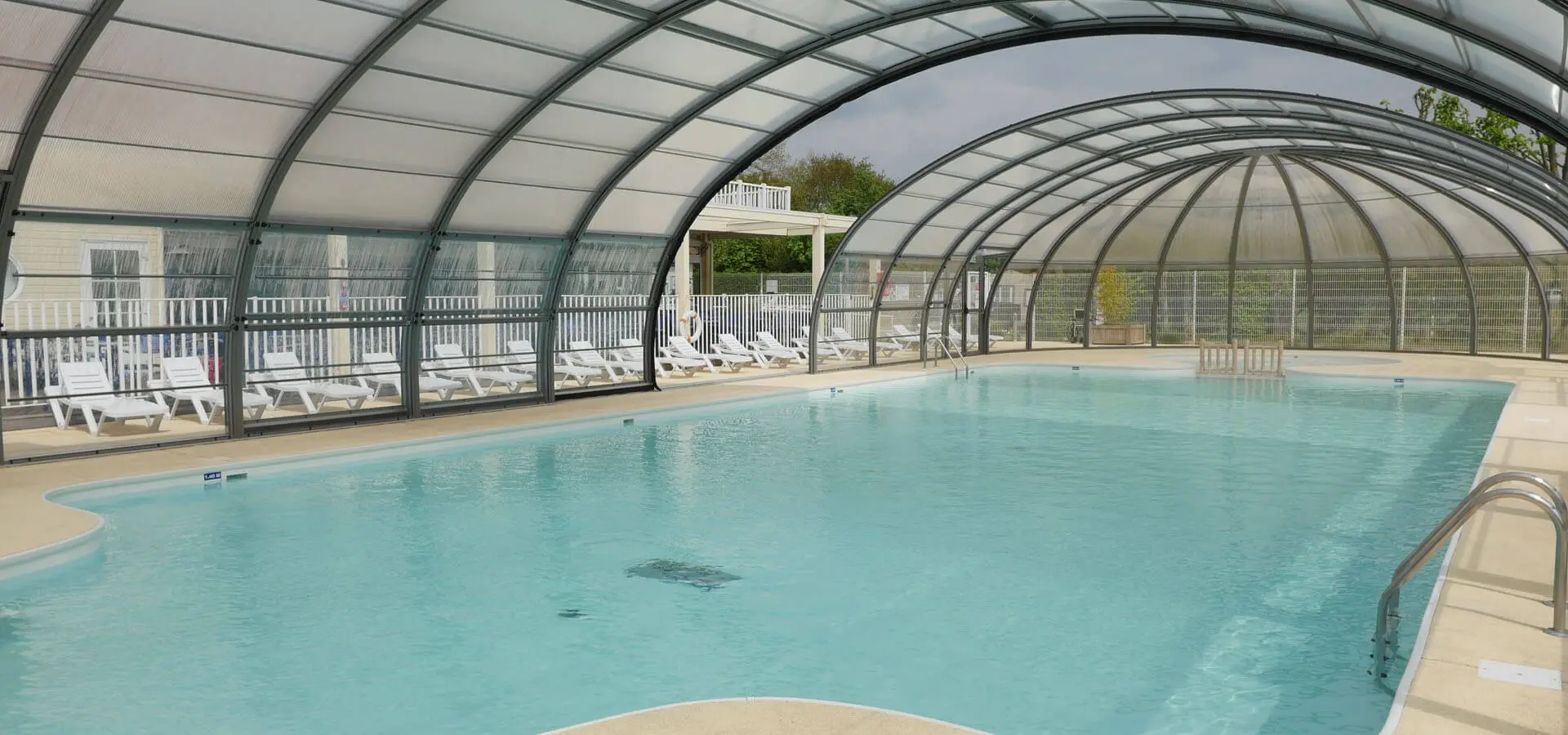 Piscine intérieure avec chaises longues à disposition.