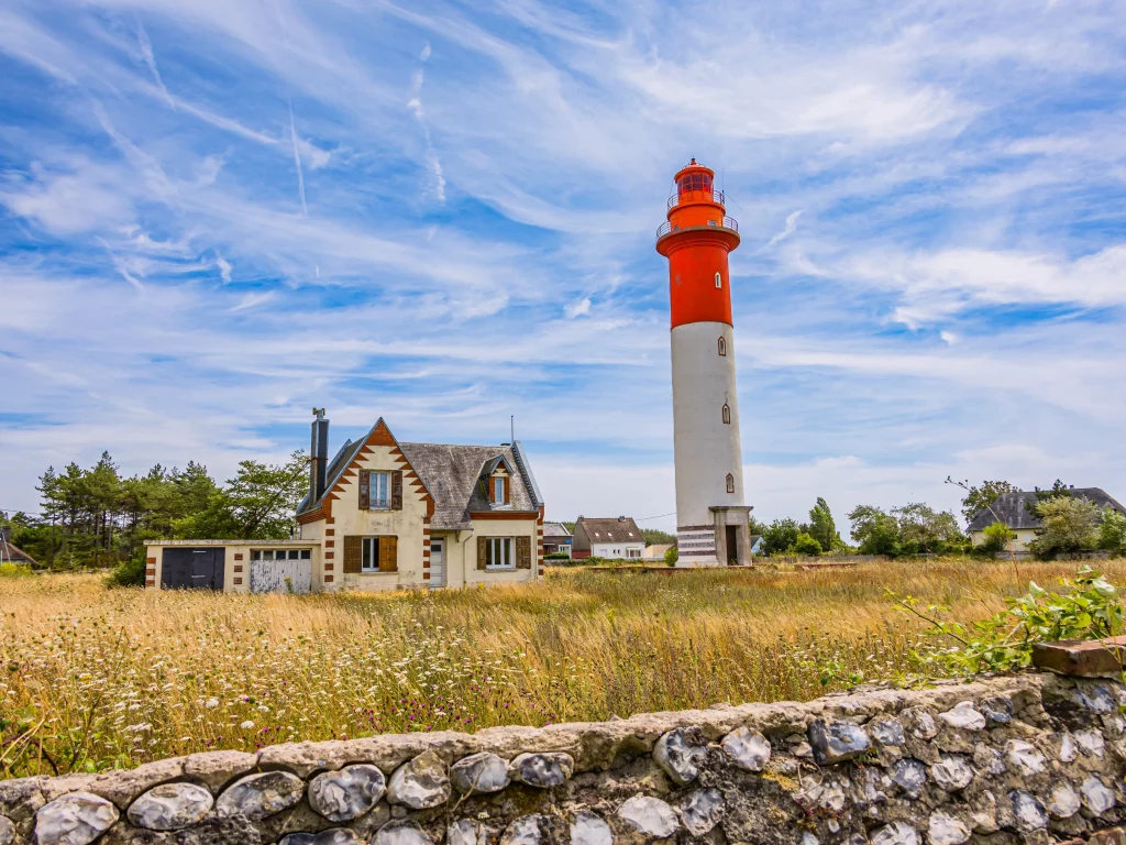 Phare orange et maison dans un champ.