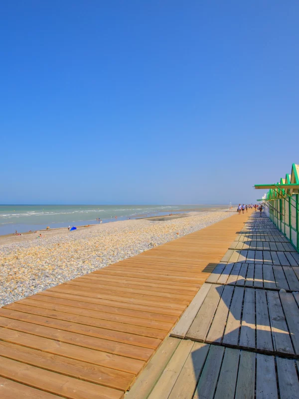 Plage avec cabines et ciel bleu dégagé.