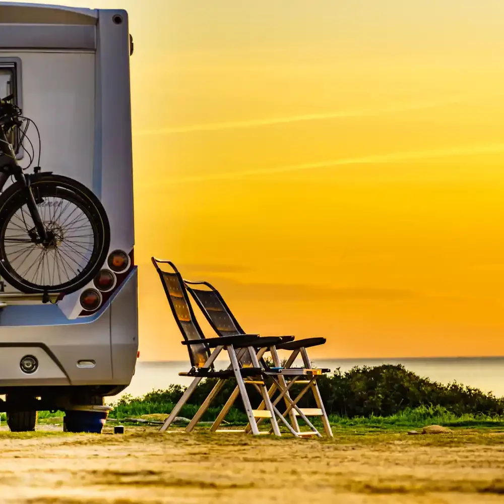 Camping-car et chaises au coucher de soleil.