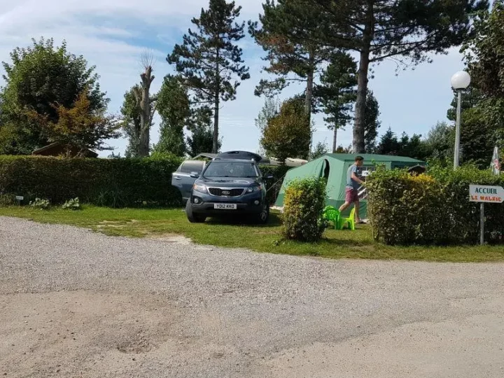 Camping avec tente et voitures en arrière-plan.