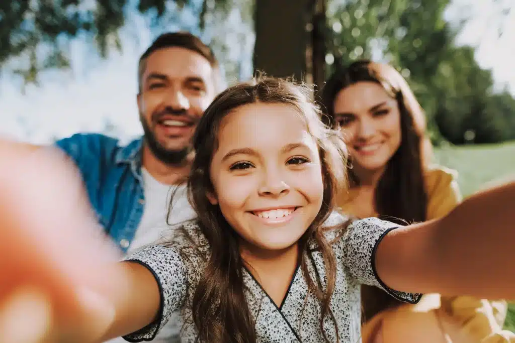 Une fille souriante prend un selfie avec ses parents.