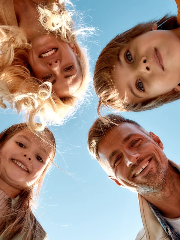 Famille heureuse souriant sous un ciel bleu.