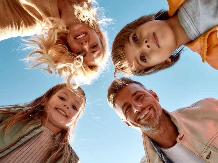 Famille heureuse souriant sous un ciel bleu.