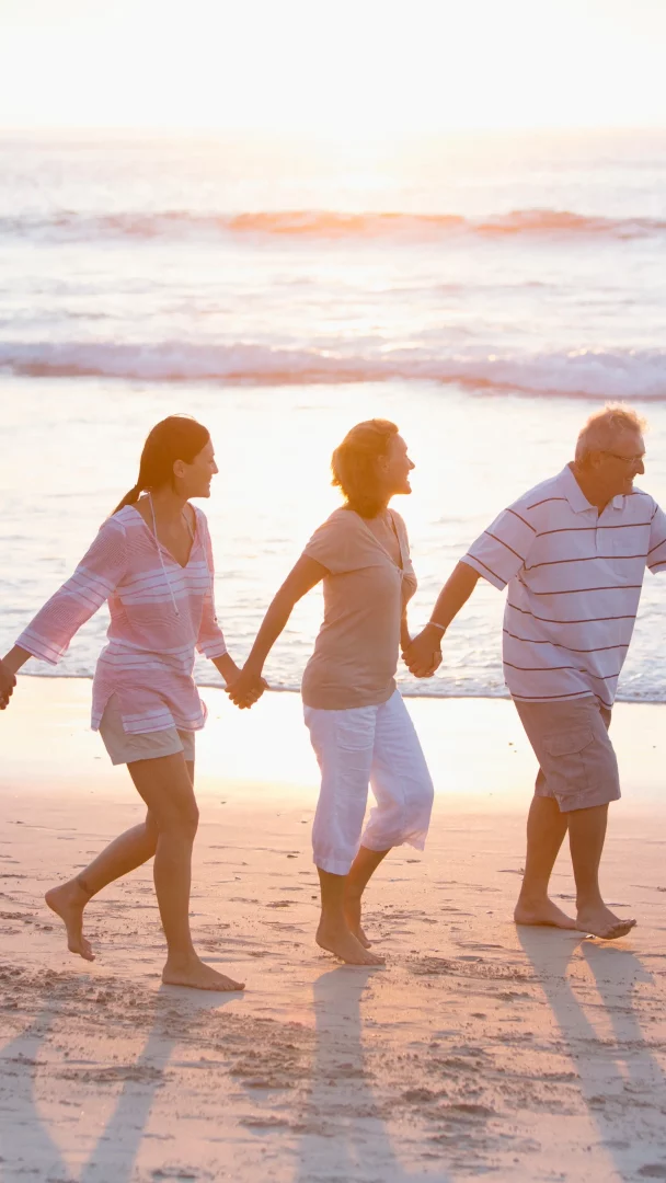 Famille heureuse marchant sur la plage au coucher du soleil