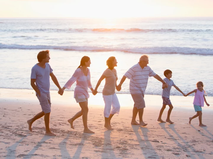 Famille heureuse marchant sur la plage au coucher du soleil