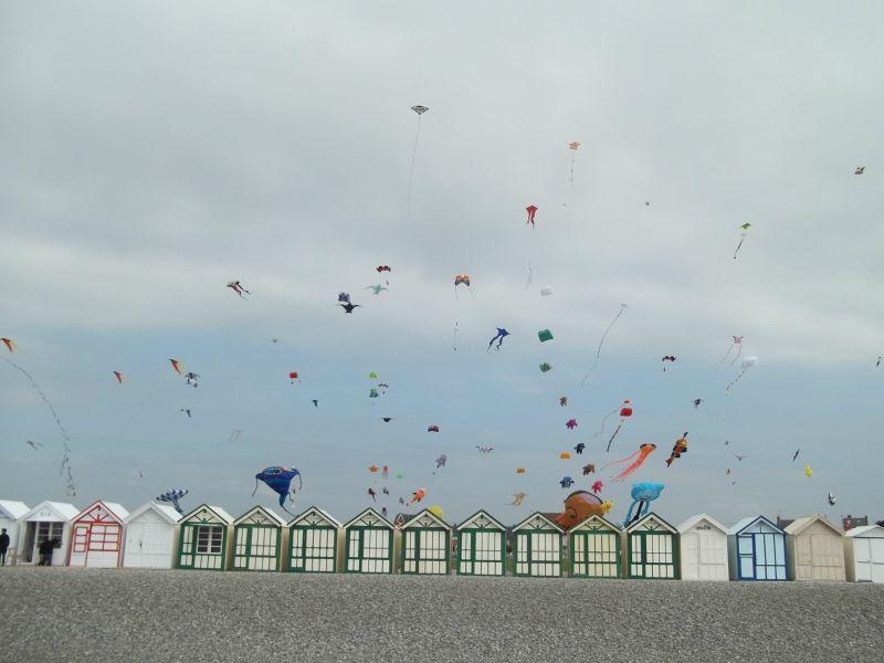 Des cerfs-volants colorés volent au-dessus des cabanes de plage.