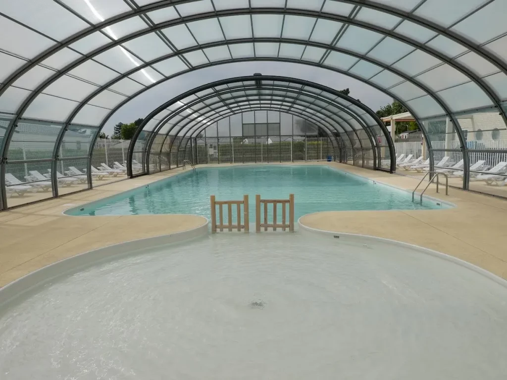 Piscine intérieure couverte avec chaises longues.