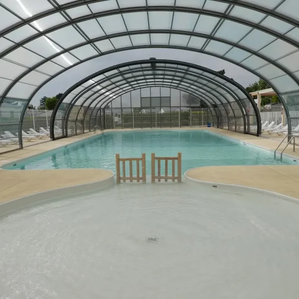 Piscine intérieure couverte avec chaises longues.