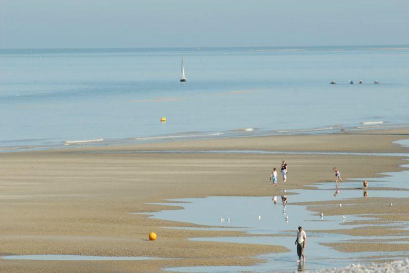 Plage tranquille avec enfants et bateau à voile.