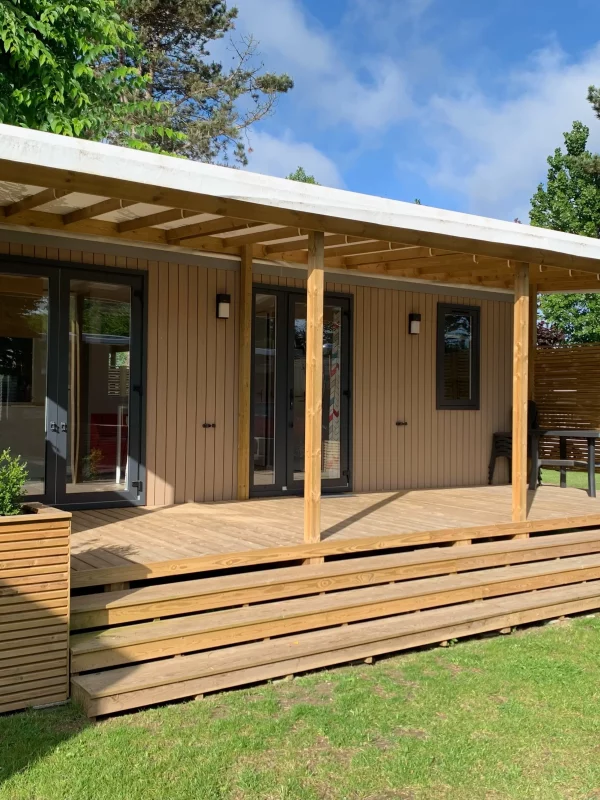Chalet en bois avec terrasse ensoleillée.