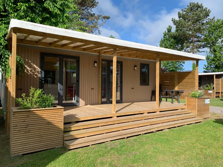 Chalet en bois avec terrasse ensoleillée.