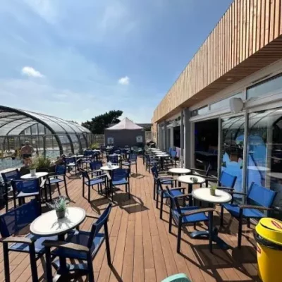 Terrasse ensoleillée avec tables et chaises bleues.