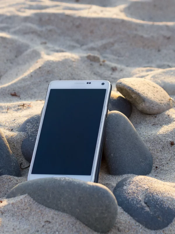 Un téléphone sur le sable et des pierres.