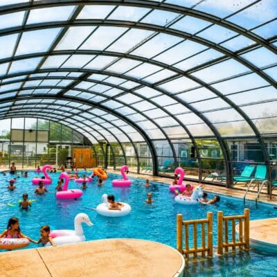 Enfants jouant dans une piscine intérieure avec toboggan.